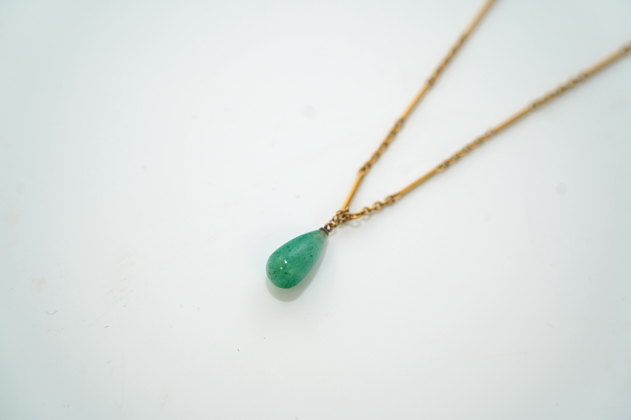 An early 20th century 15ct and single stone pear shaped simulated jade set pendant necklace, overall 46cm, gross weight 6 grams. Condition - good